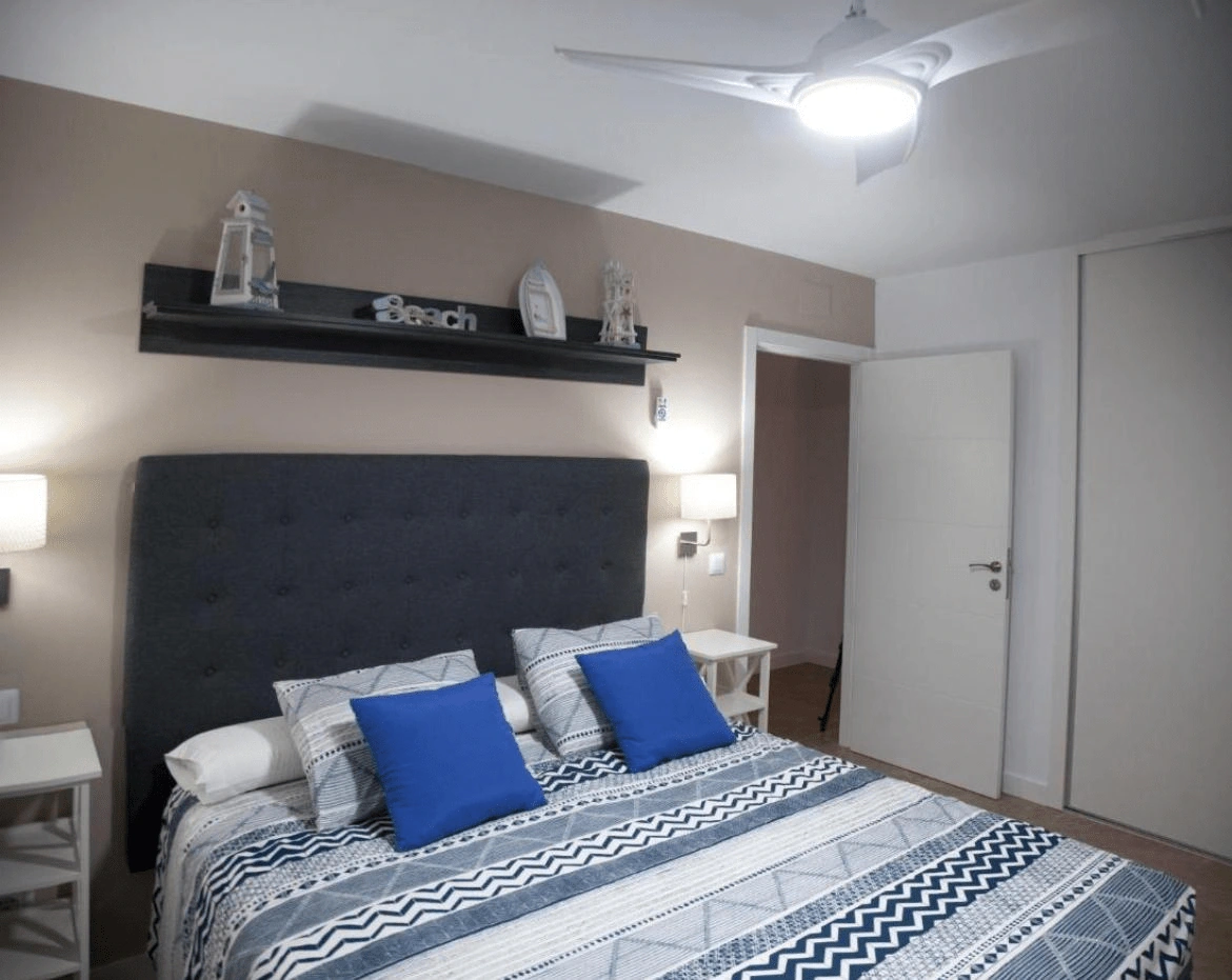 Cama de matrimonio con cabecero azul y ropa blanca